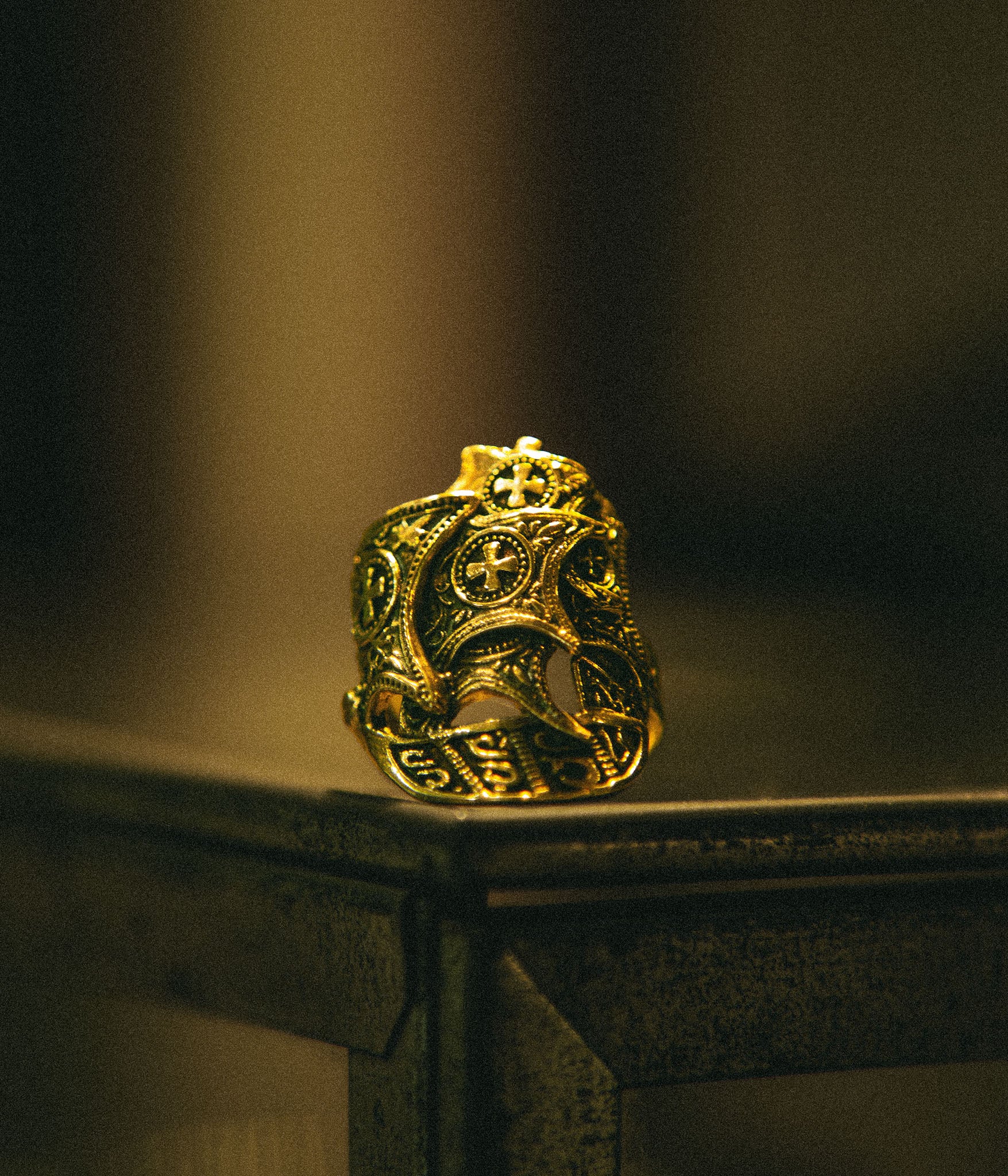 Gold ring with intricate design on a dark background
