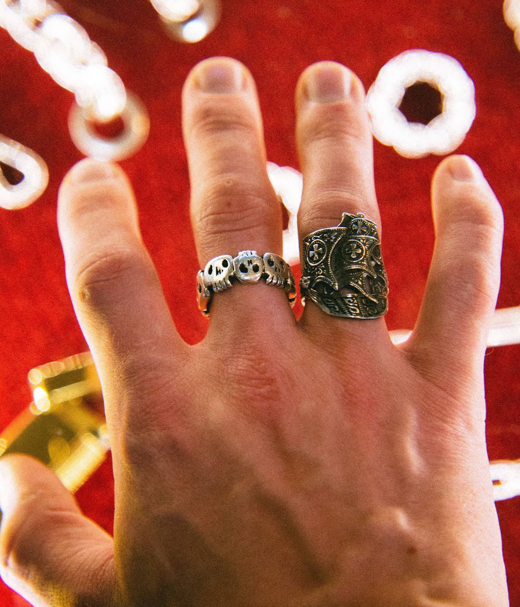 Hand wearing two rings with a red background