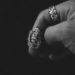 Close-up of a hand wearing two ornate silver rings on a black background