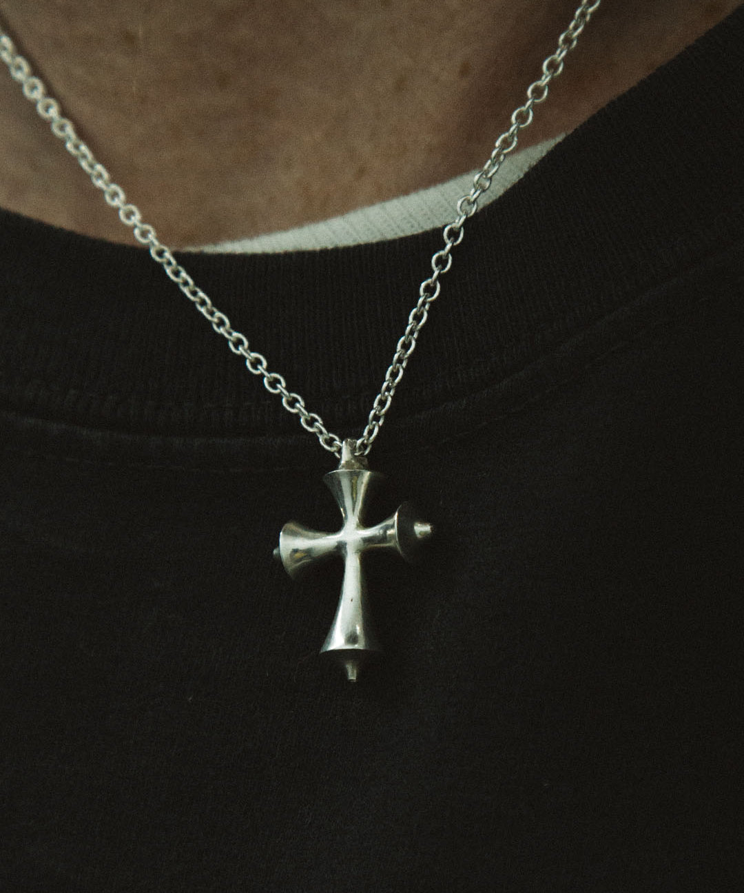 Silver cross necklace on a black background