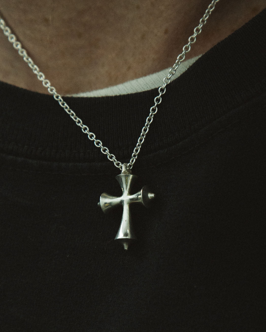 Silver cross necklace on a black background