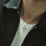 Person wearing a black leather jacket with a cross necklace.