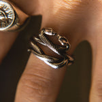 Close-up of a person wearing a silver snake-shaped ring on their finger.