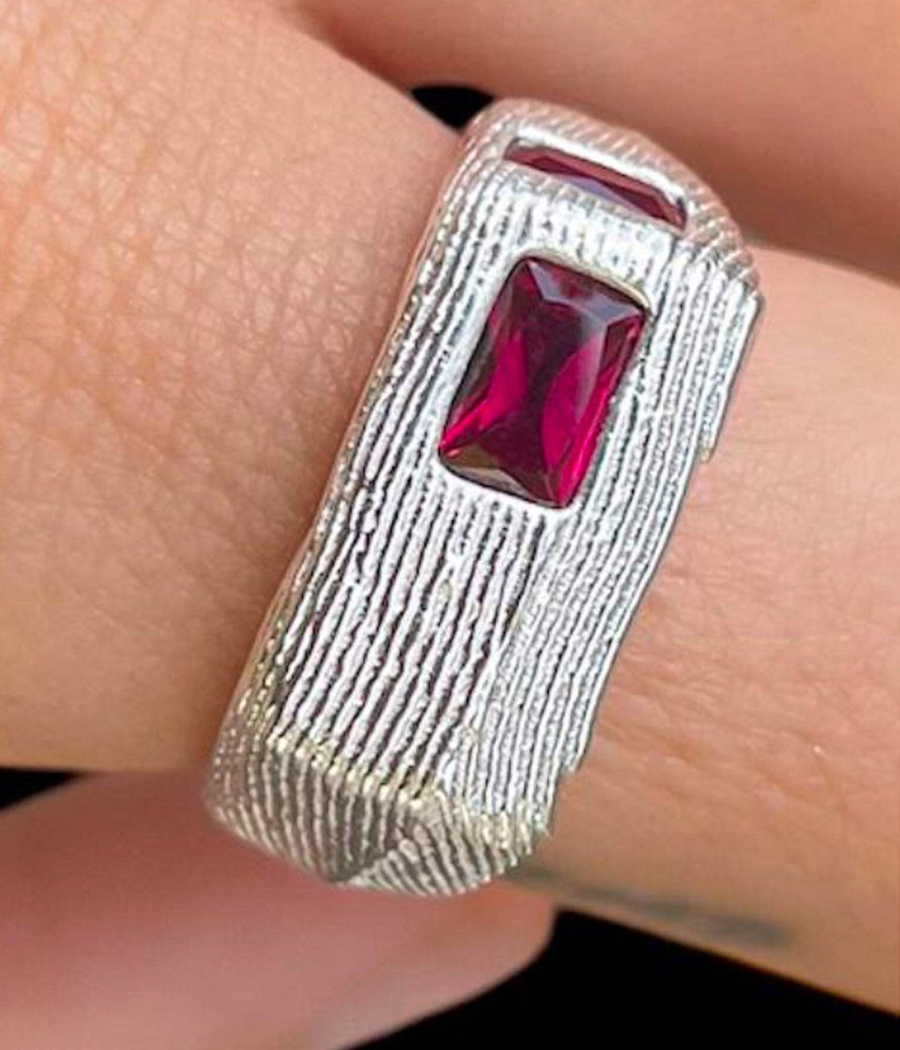 Silver ring with a red gemstone on a finger