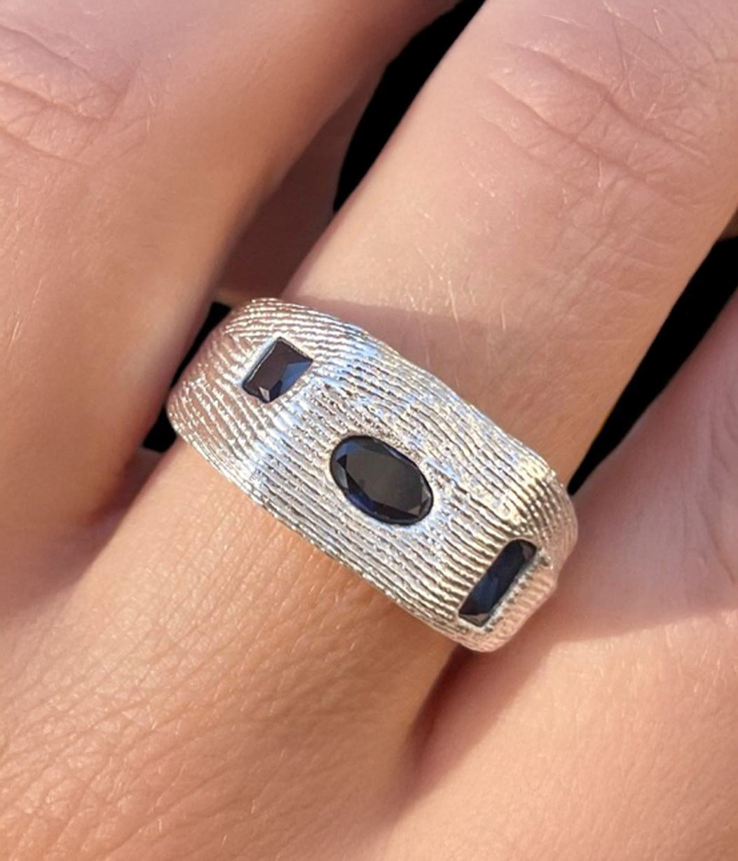 Silver ring with black stones on a finger