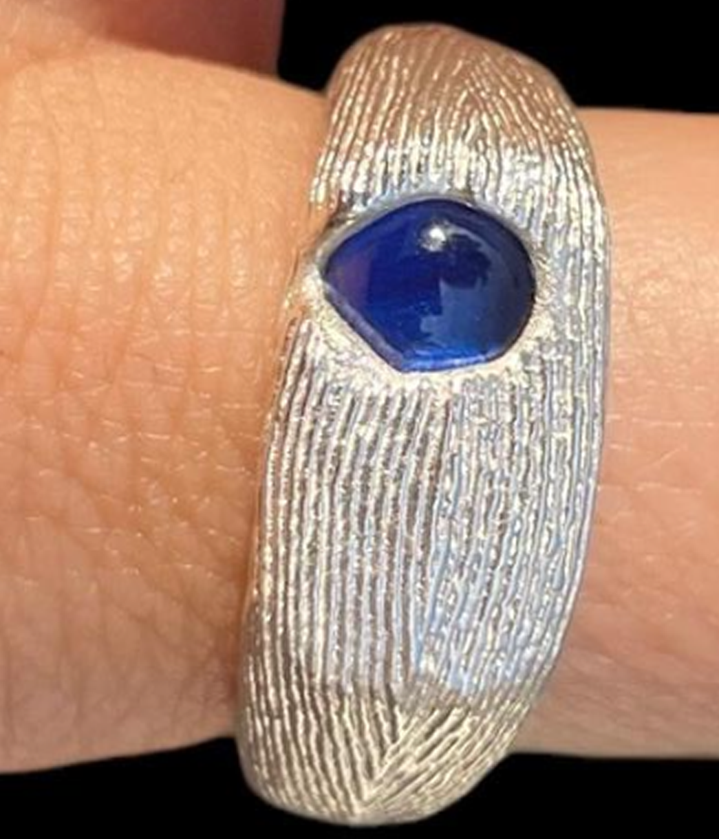 Silver ring with a blue stone on a finger
