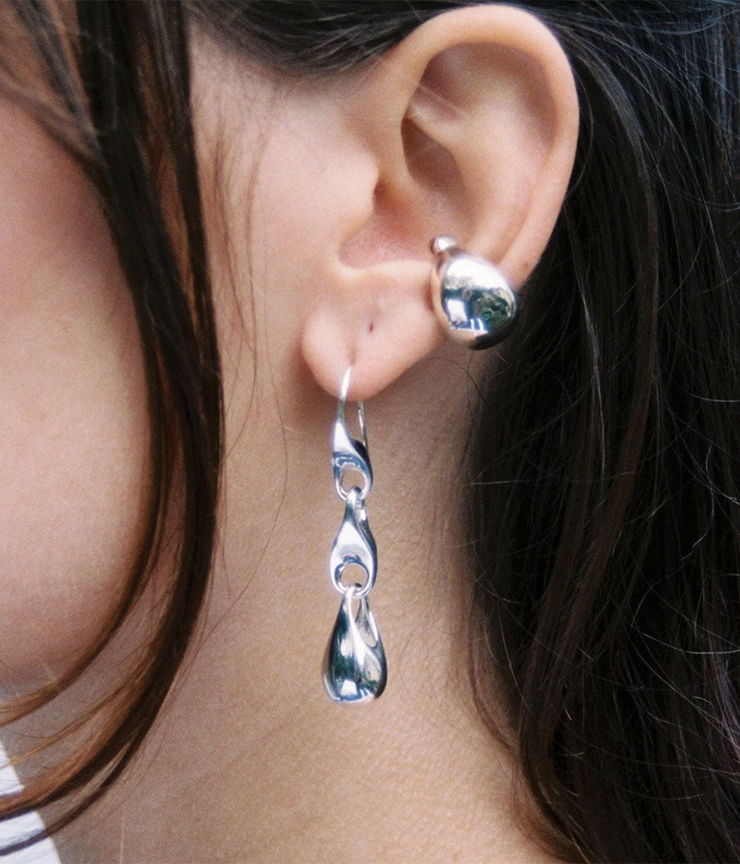 Close-up of a person wearing silver earrings with a dark background