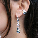 Close-up of a person wearing silver earrings with a dark background