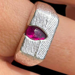 Silver ring with a pink gemstone on a finger