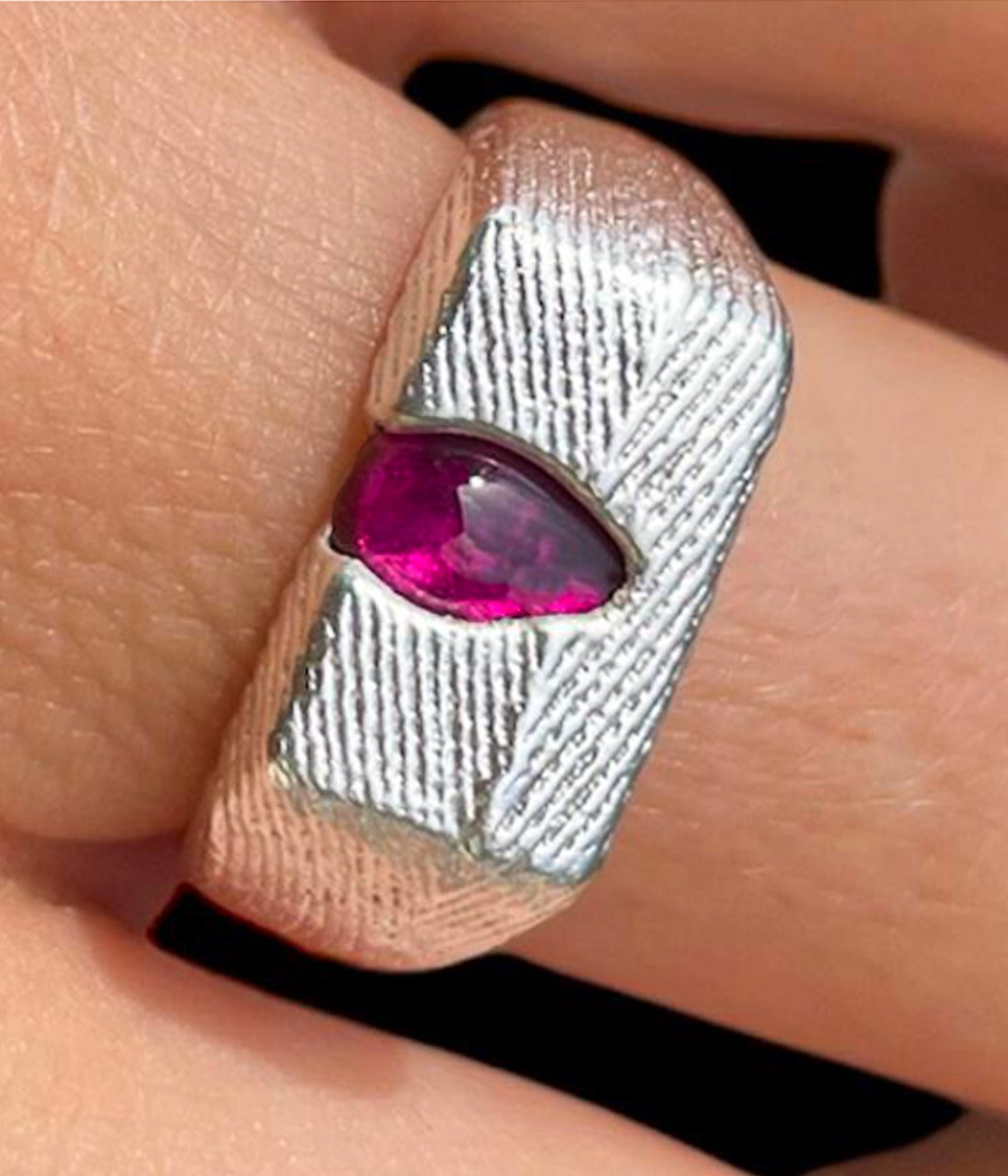 Silver ring with a pink gemstone on a finger