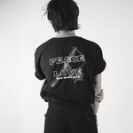 Person wearing a black t-shirt with 'Peace & Love' text on the back, standing against a white background.