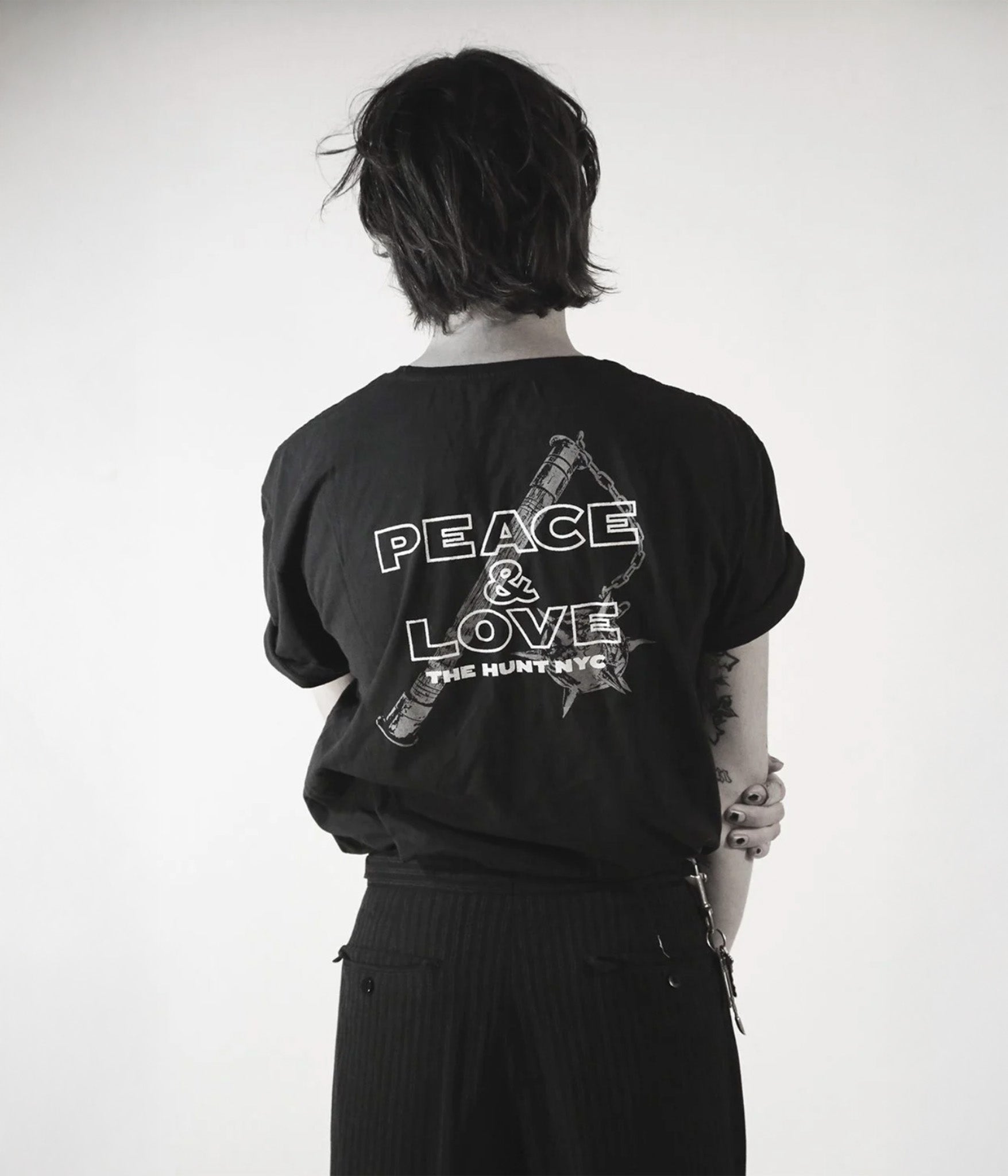Person wearing a black t-shirt with 'Peace & Love' text on the back, standing against a white background.