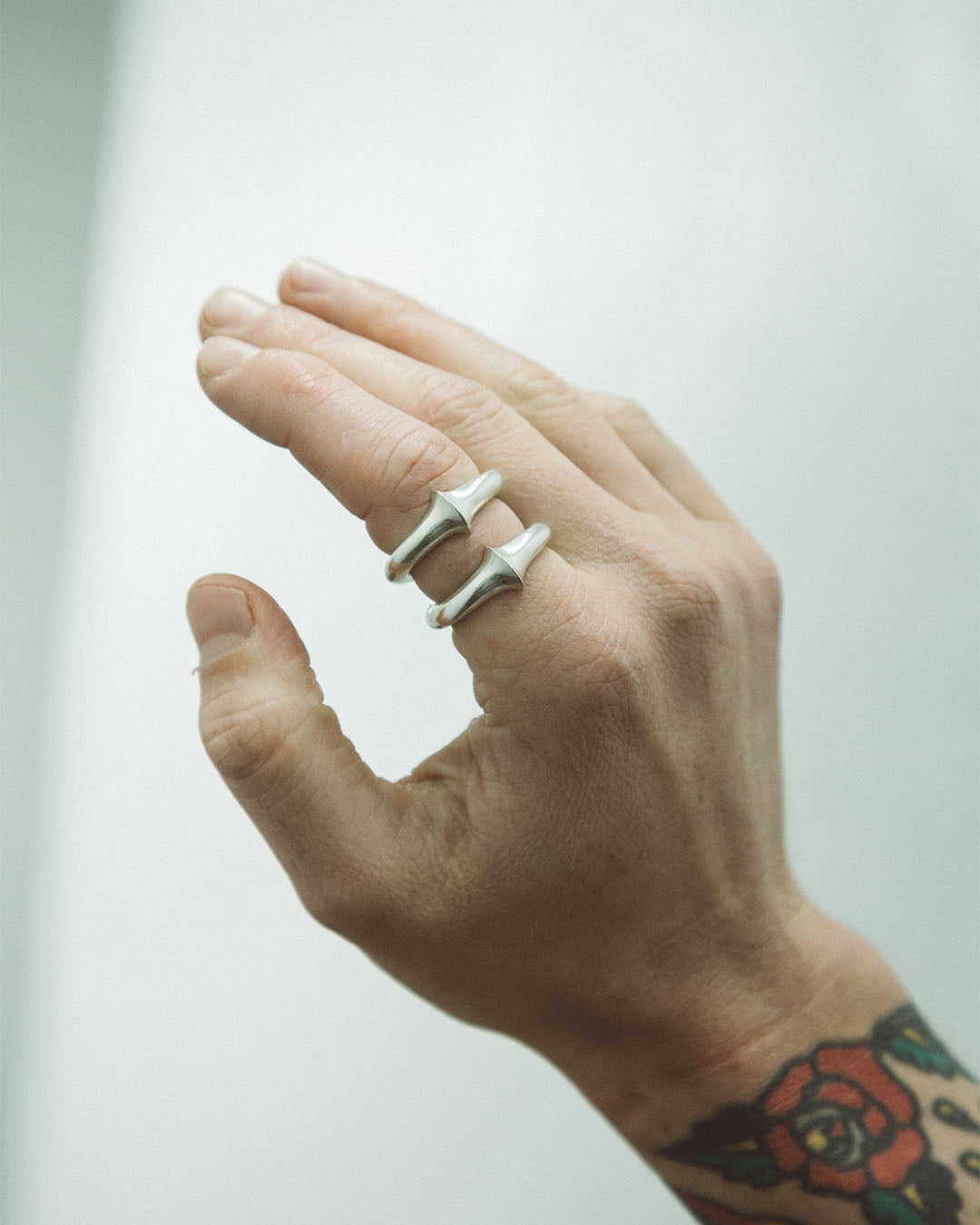 Hand wearing two silver rings with a blurred background