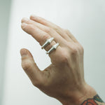 Hand wearing two silver rings with a blurred background