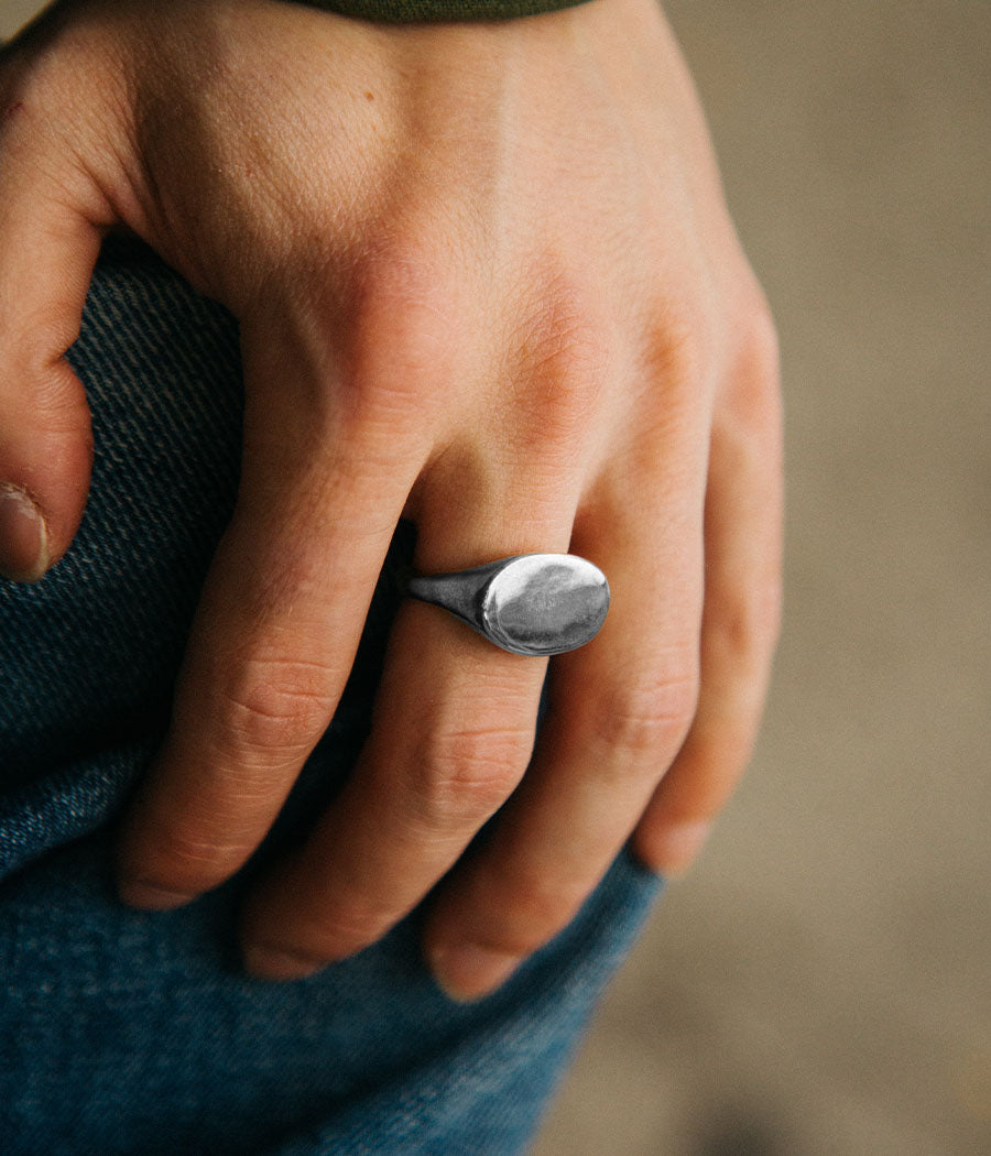 Hand wearing a silver ring with a blurred background