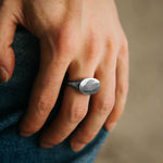 Hand wearing a silver ring with a blurred background