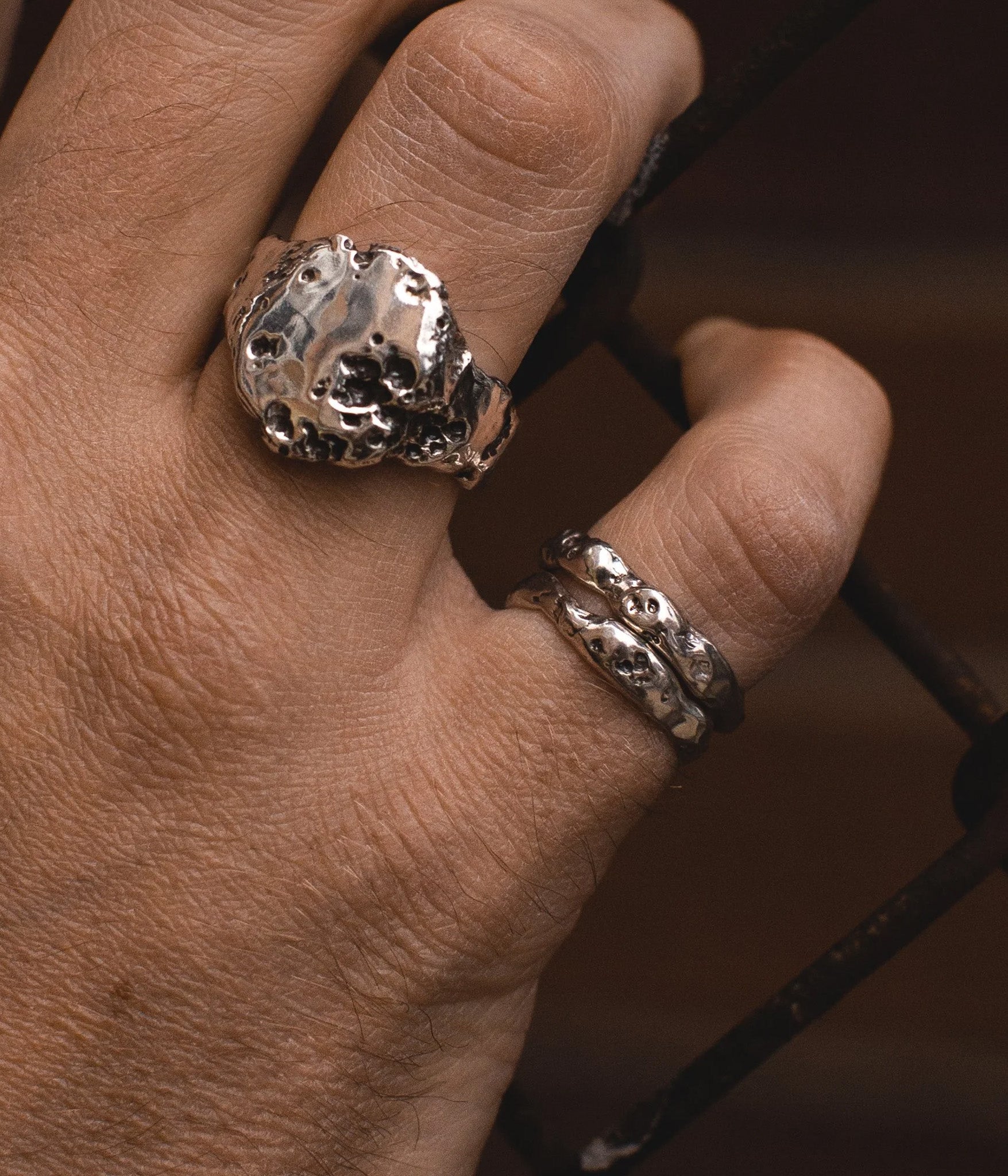Close-up of a hand wearing two silver rings with a textured design.
