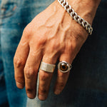 Hand wearing a silver ring and bracelet on a denim background