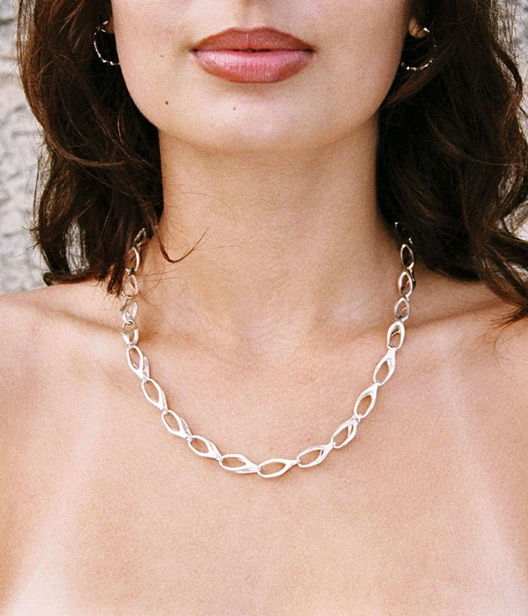 Silver chain necklace worn by a person with a neutral background