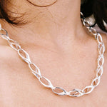 Silver chain necklace worn around the neck