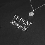Black shirt with 'LE HUNT Lounge NYC' text and a necklace on a black background