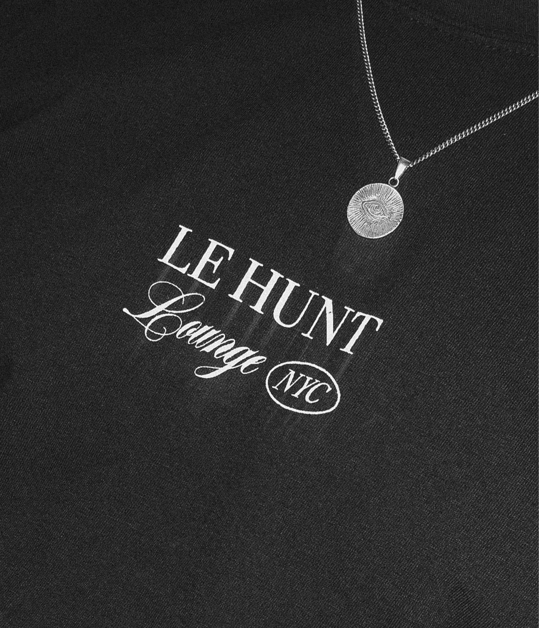 Black shirt with 'LE HUNT Lounge NYC' text and a necklace on a black background