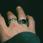 Hand wearing two rings with a dark background
