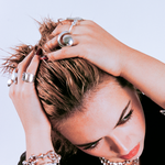 Woman with styled hair and jewelry against a light background