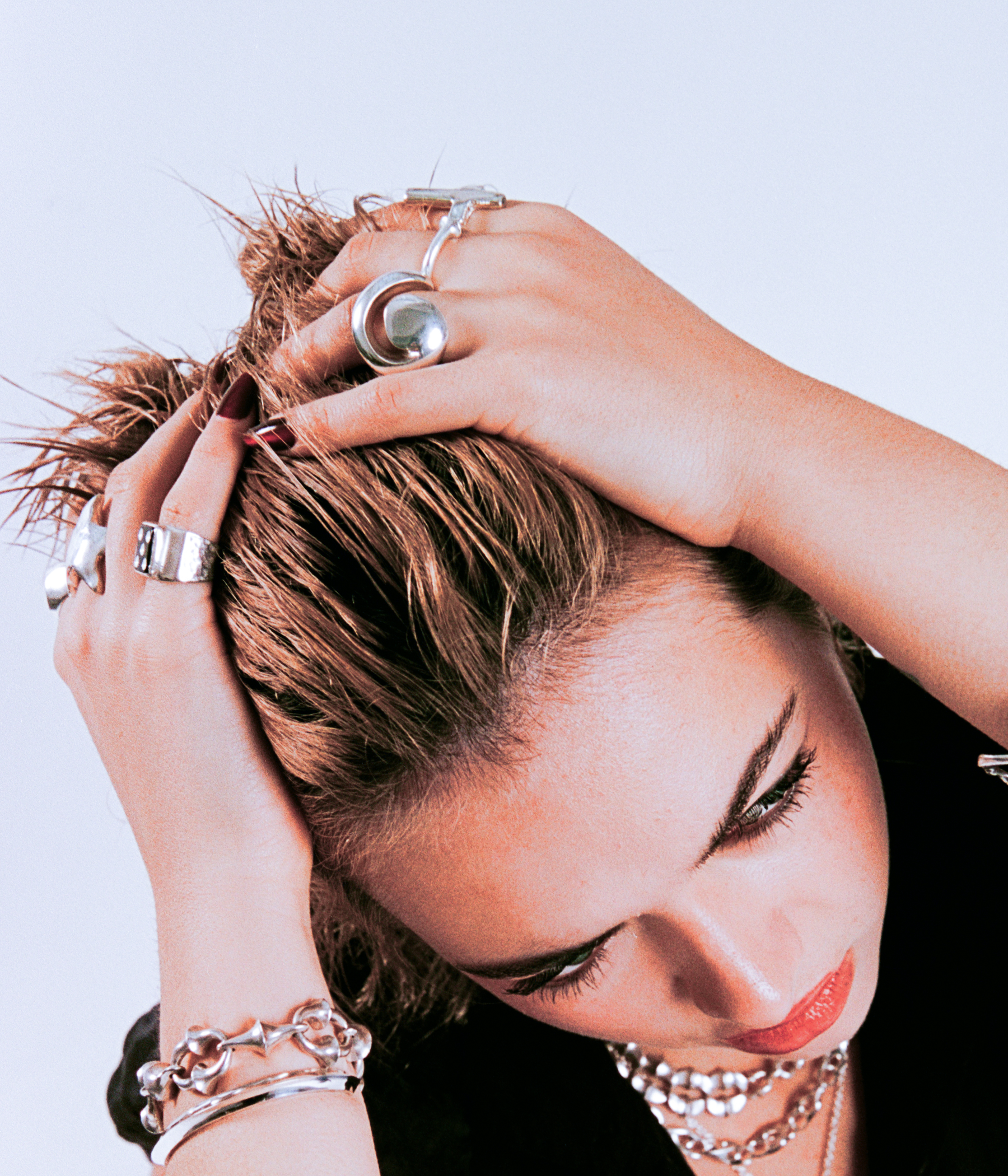 Woman with styled hair and jewelry against a light background