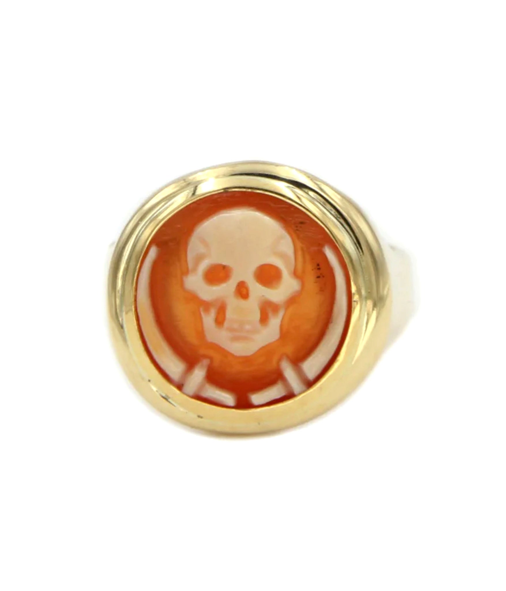 Gold ring with a skull design on an orange background