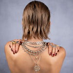Person wearing multiple necklaces with a plain background