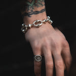 Hand wearing a silver chain bracelet on a dark background