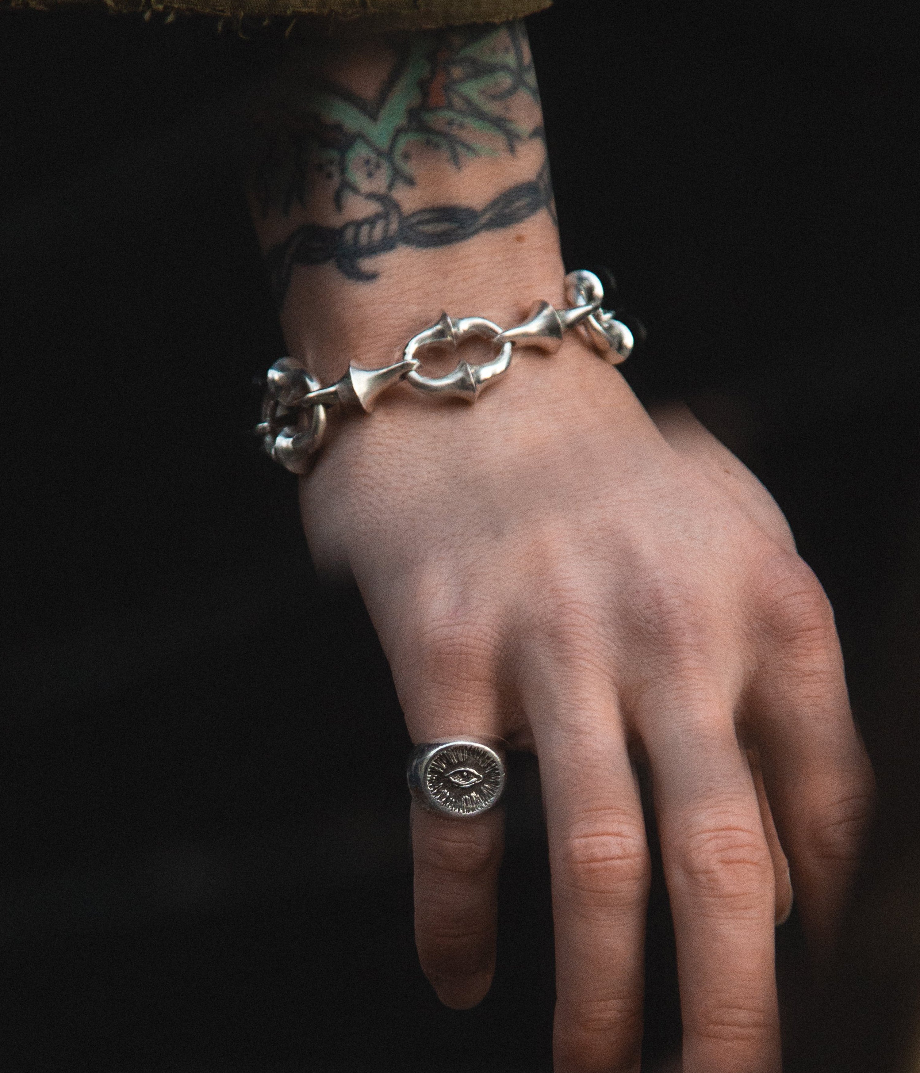 Hand wearing a silver chain bracelet on a dark background