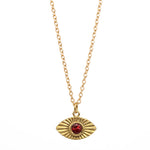 Gold necklace with a red gemstone eye pendant on a white background