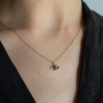 Gold necklace with a pendant on a person wearing a black top.