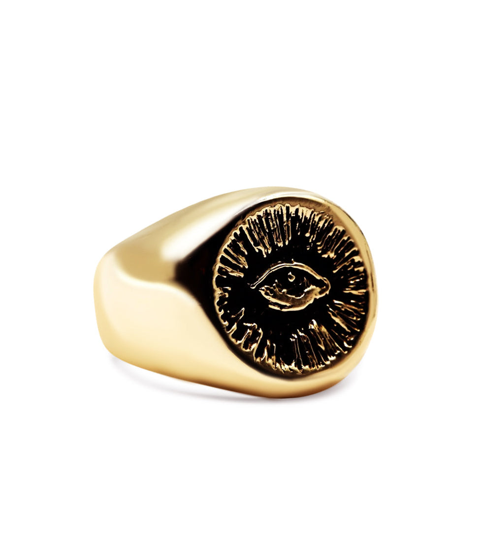 Gold ring with a face design on a white background