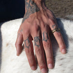 Hand with tattoos and a gold ring on a white animal's fur