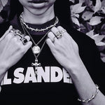 Person wearing multiple necklaces and rings with a black shirt 