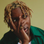 Person with braided hair wearing a green shirt against a yellow background