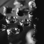 A close-up black and white photograph of several clear glass rings displayed on a reflective surface, with shallow depth of field and blurred reflections in the background.