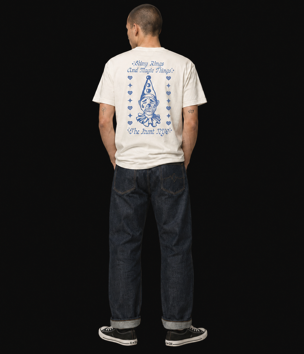Person wearing a white t-shirt with blue graphics and text, standing against a black background