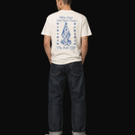 Person wearing a white t-shirt with blue graphics and text, standing against a black background
