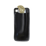 A black leather key pouch with a metal grommet, shown holding a brass key, isolated on a white background.