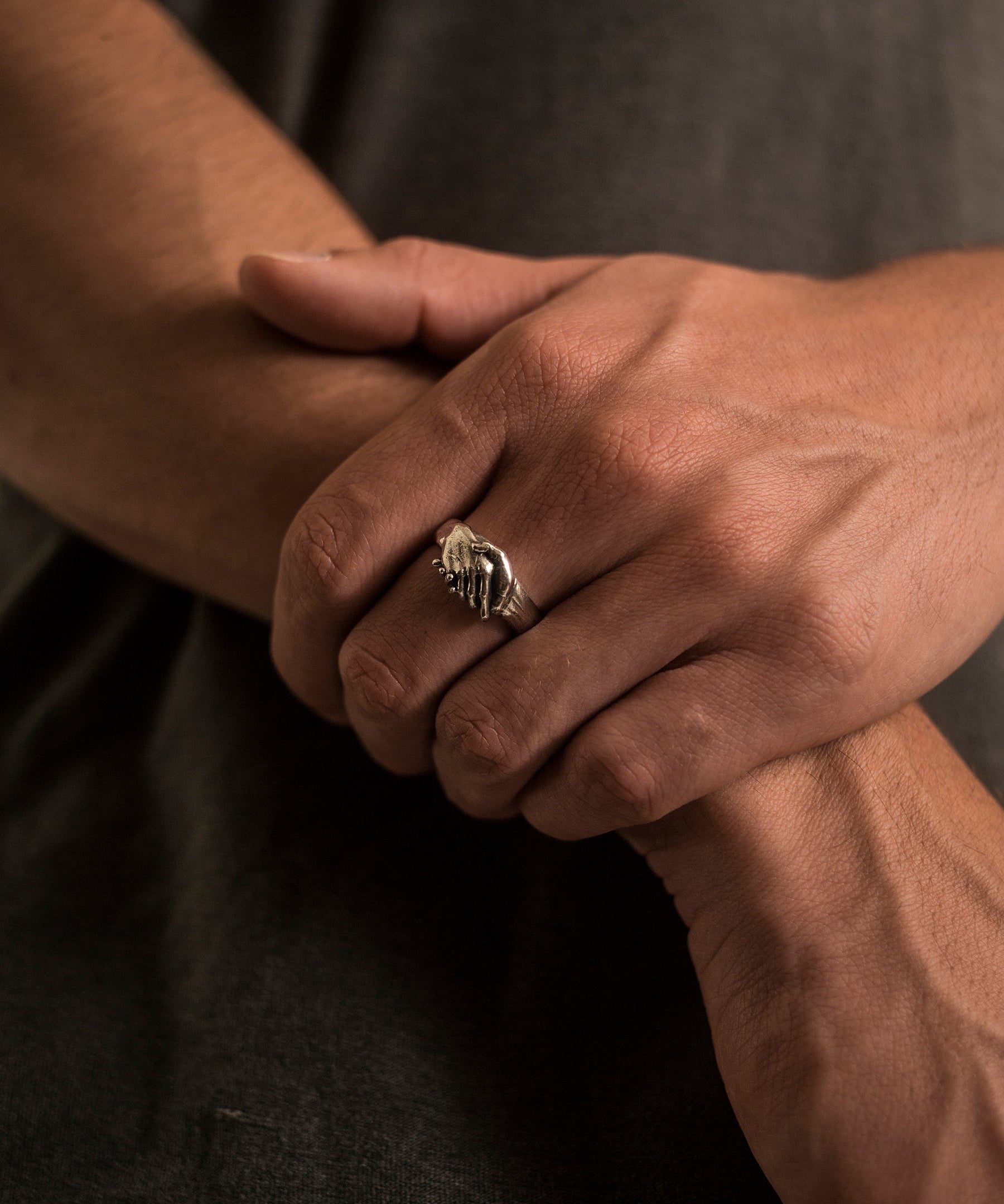 Close-up of a hand wearing a ring with a dark background