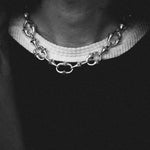 Close-up of a person wearing a chain necklace with a blurred background