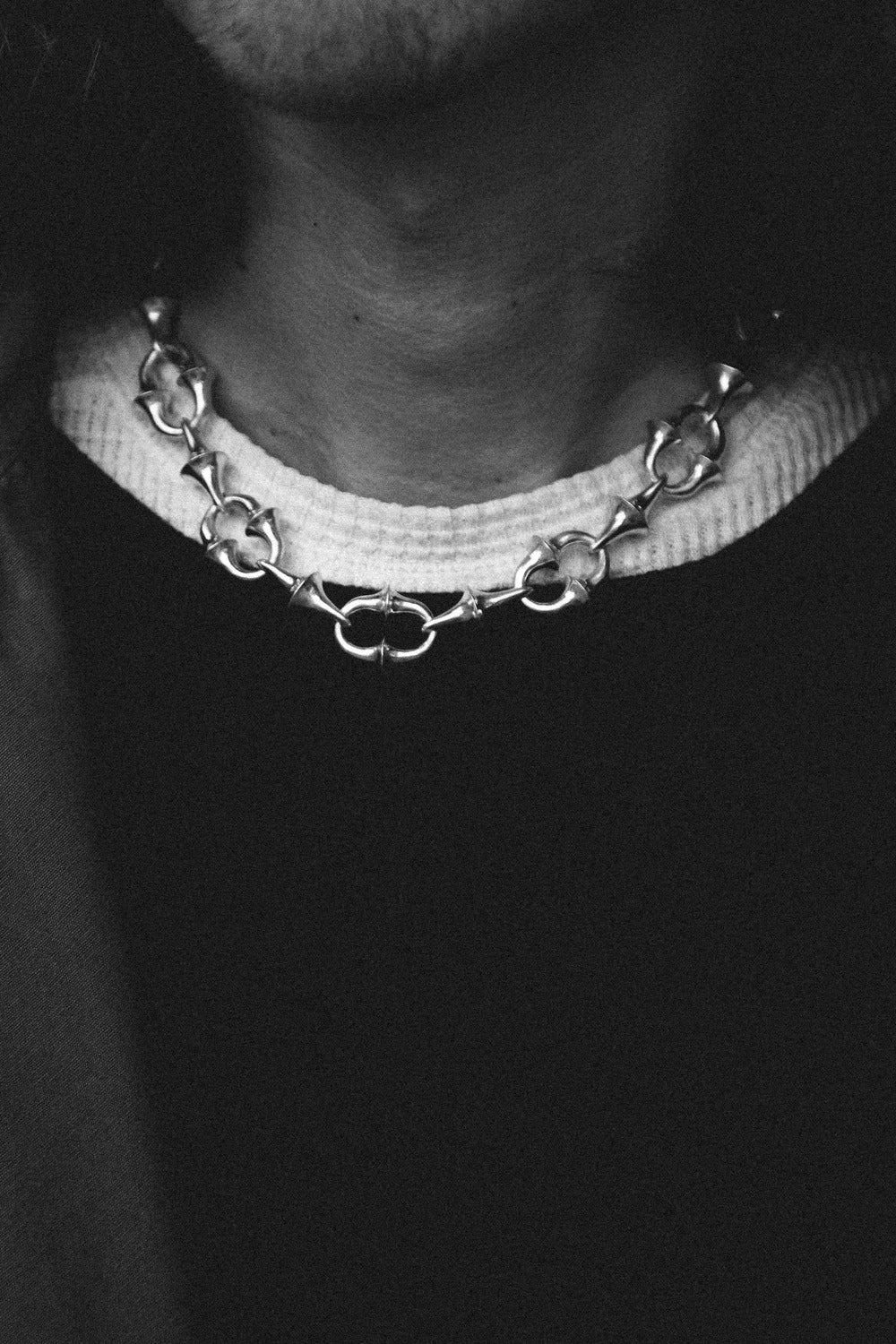 Close-up of a person wearing a chain necklace with a blurred background