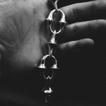 Silver bracelet held in a hand against a dark background