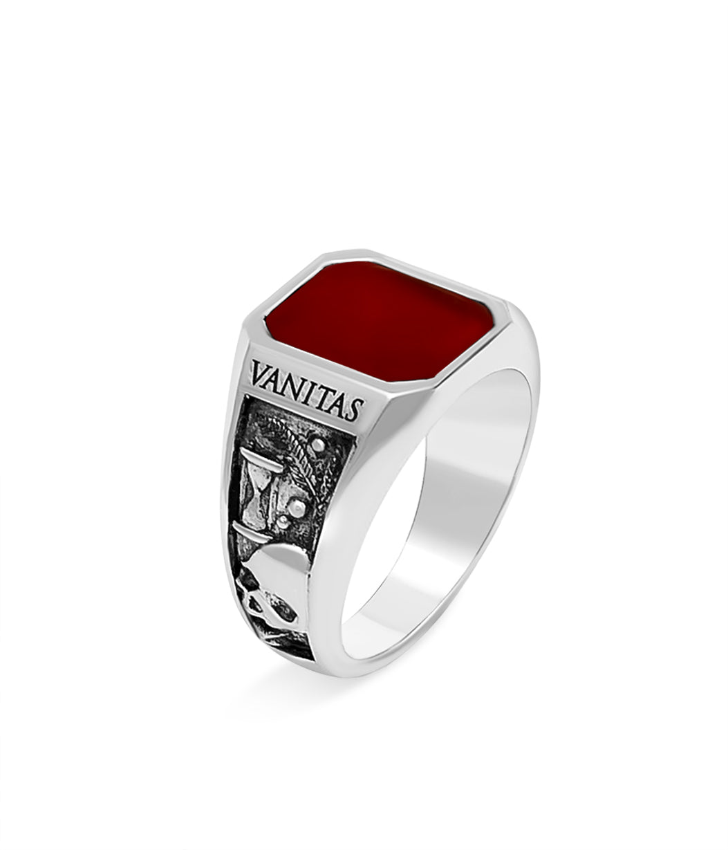 Silver ring with red stone and 'Vanitas' engraving on a white background