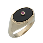 Gold ring with a black stone and red gemstone on a white background